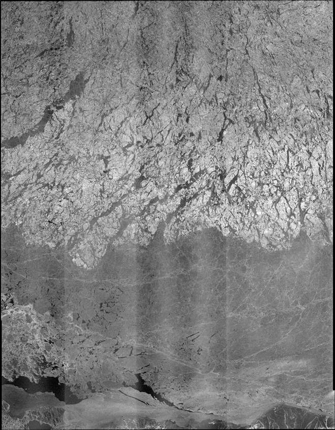 The upper portion of this RADARSAT-2 ScanSAR Wide synthetic aperture radar image obtained on May 15, 2014, is multiyear pack ice. The lower, darker portion is thinner, first-year ice. The north coast of Alaska is just visible along the bottom. The initial instrument array for the Marginal Ice Zone experiment was deployed in March 2014 in the multiyear ice cover. Photo courtesy of U.S. Navy.