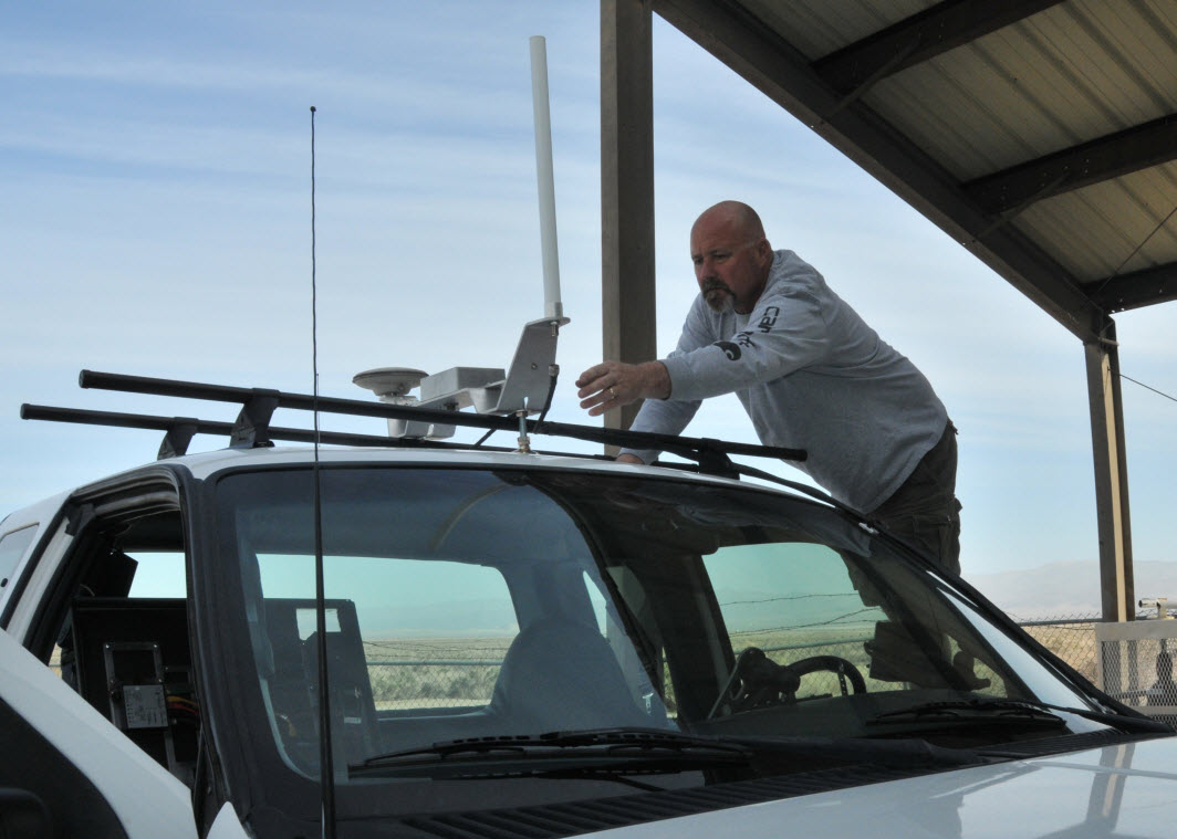 Reed Robinson, a control software engineer at Naval Air Warfare Center Weapons Division, demonstrates how the Shoot-able Remote Threat Ground Target (SRTGT) system puts a vehicle into gear while being remotely driven. There are five motors that operate the mechanical functions of the SRTGT truck. The “box,” left, contains the computer hardware and software that is used for the vehicle to receive commands from the operator at the base station. U.S. Navy photo.