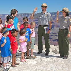 Group of children standing with male and female National Park Service rangers at the Grand Canyon