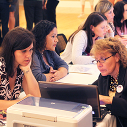 A group of females at a resume writing workshop seated on either side of a table 