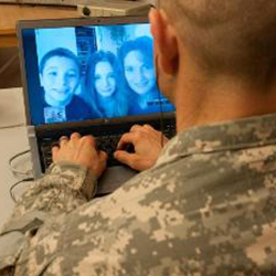 Male service member video chatting with family on laptop