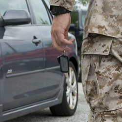 A service member with keys in his hand standing next to a car