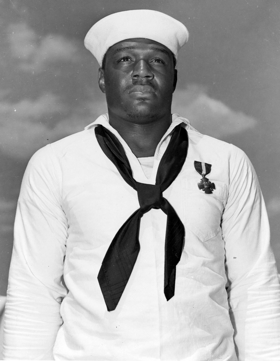 Doris Miller, Mess Attendant Second Class, USN, just after being presented with the Navy Cross by Admiral Chester W. Nimitz, on board USS Enterprise (CV-6) at Pearl Harbor, 27 May 1942. The medal was awarded for heroism on board USS West Virginia (BB-48) during the Pearl Harbor Attack, 7 December 1941. Official U.S. Navy Photograph, now in the collections of the National Archives. Catalog #: 80-G-408456