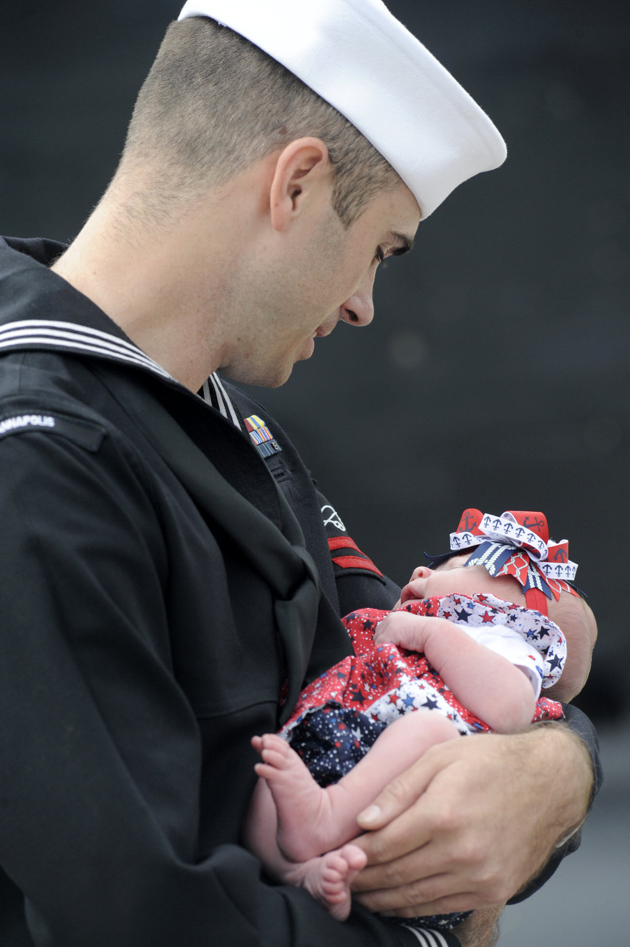 Sonar Technician (Submarine) 2nd Class William Wade holds his daughter for the first time moments after the Los Angeles-class attack submarine USS Annapolis (SSN 760) arrives at Submarine Base New London. U.S. Navy photo by John Narewski.