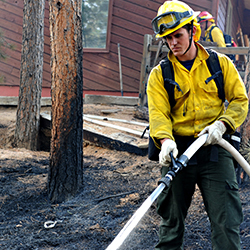 Firefighter spraying water on a wildfire.