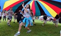 Children play parachute during a fitness-themed event. The festivities were part of a campaign to combat childhood obesity. (U.S. Air Force photo by Staff Sgt. Austin May)