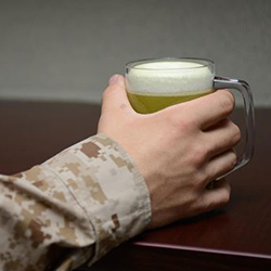 A service member’s hand holding a mug of beer