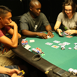 Men and women playing cards at a poker table.