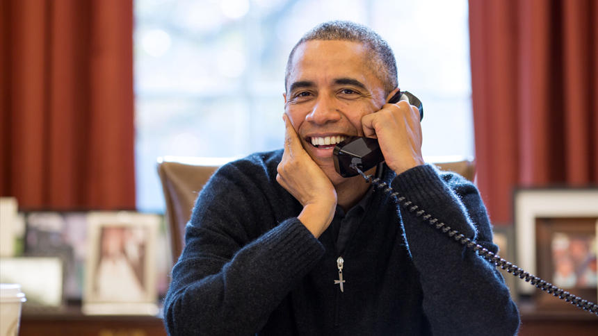 President Obama smiles while speaking on the phone in the Oval Office