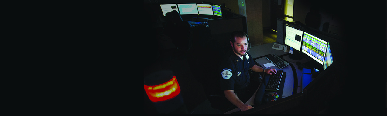 911 call taker at workstation with lit computer screens