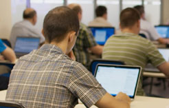 Photo of back of people using computers in a classroom setting