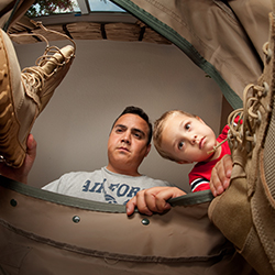 Father and son putting military boots into a bag