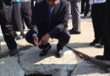 Photo of Secretary Foxx examining a hole in Kansas City sdiewalk