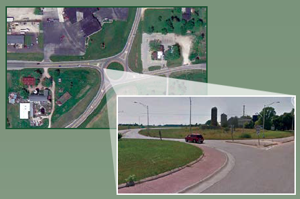 Image shows an overhead shot of a roundabout and a car exiting a roundabout.