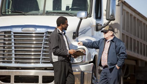 Individual talking in front of a large truck