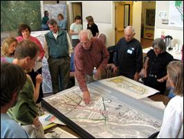 Photo. Image of a group of people gathered around a map.