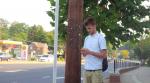 Young man with phone waiting at bus stop