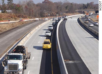 Photo. A highway has been divided with a concrete barrier wall so that traffic runs on one side while work progresses on the other.