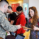 Picture of a service member handing out information to a young lady.