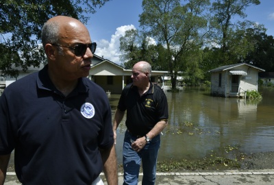 Secretary Johnson walks up the bank of a flooded road