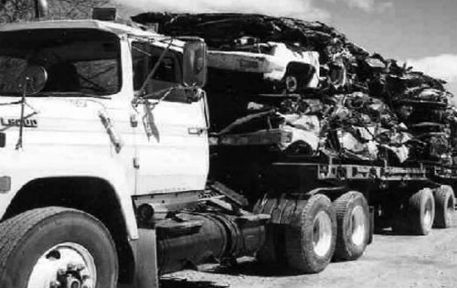 Black and White photo of a truck carrying crushed cars
