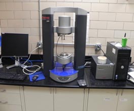 The image shows a dynamic shear rheometer with parallel plates system.  The cement paste is sandwiched between the two parallel plates and then the shear stress and strain are measured as the upper plate is oscillated.