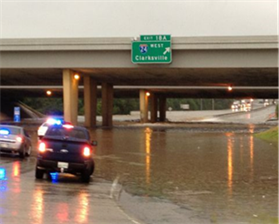 Photograph of a flooded highway with emergency vehicles on the road.