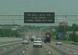 An image of an overhead Display Message Sign (DMS) displaying traveler time information.