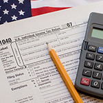 Calculator, tax forms, a pencil and an American flag displayed together