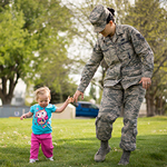 A service member walking with her daughter