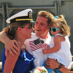 Service member reunited with his wife and child after deployment.