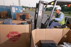 a man driving a forklift laden with old electronics