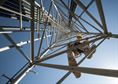 Senior Airman James Vrtis, a 57th Operations Support Squadron airfield systems technician, descends a ground-to-air radio tower on Nellis Air Force Base, Nev., Oct. 6, 2015. Airfield systems specialists must periodically perform preventative maintenance inspections on ground-to-air radio towers, which stand as tall as 180 feet. (U.S. Air Force photo/Staff Sgt. Siuta B. Ika)