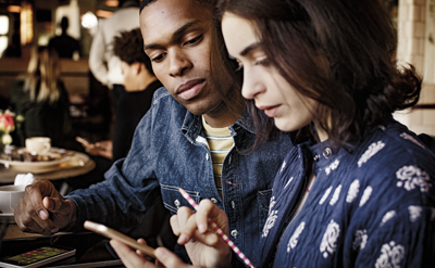 Two people looking at the screen of a phone, learn about collaborating with others in Office