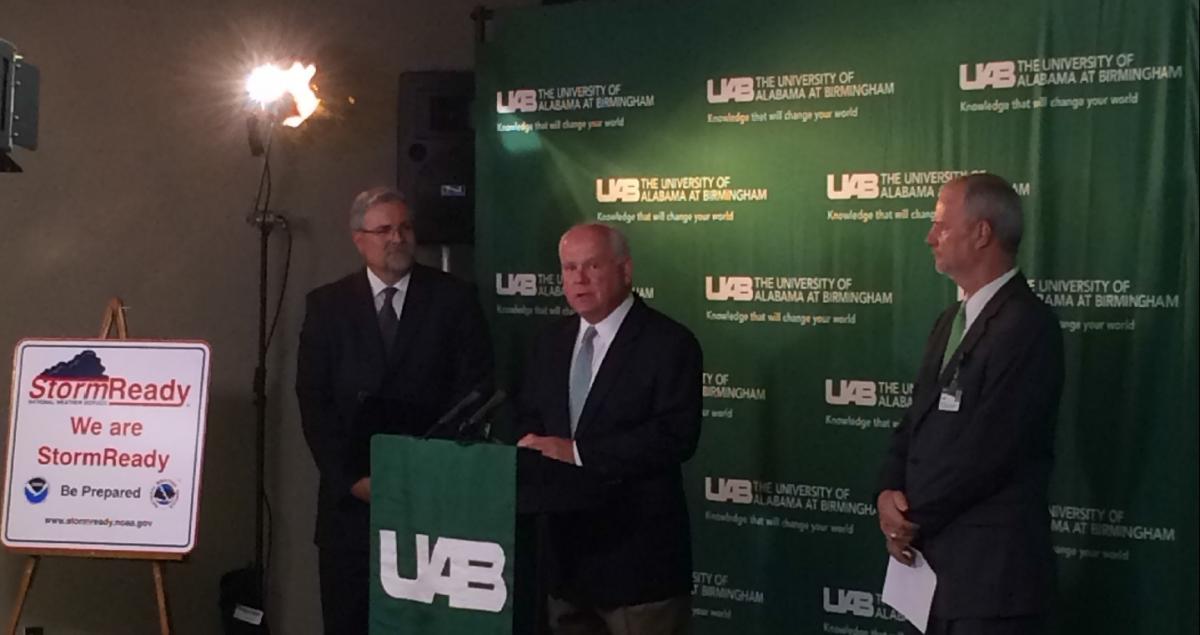 UAB President Dr. Ray Watts at podium with Randy Pewitt on his left and NWS Meteorologist Jim Stefkovich on his right.