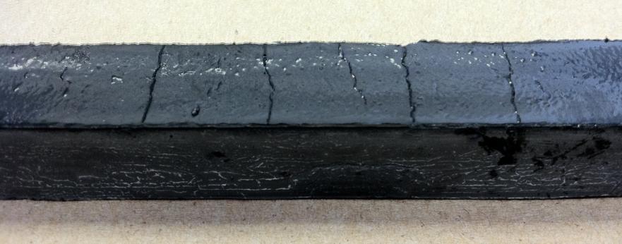 Photo of a long black beam showing very shallow vertical cracks without fractures when CNF is used. The beams did not fracture through the shallow cracks during the bending test.