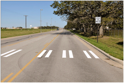 Figure 1. Photo. Example of bar pairs markings installed for this study. This photo shows an example of the bar pair markings installed at one of the study sites. Each bar pair consists of two 8-inch strips of parallel, white longitudinal markings separated by 8-inch spacing. The strips are 10 ft long. The bar pairs are located on the edge and in the middle of the travel lanes.