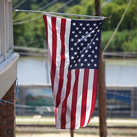 The American flag hangs over the porch of a house.