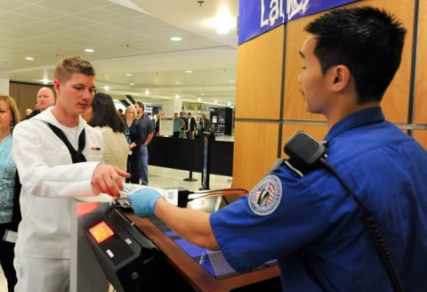 A US Navy sailor presents his travel documentation to a TSA officer