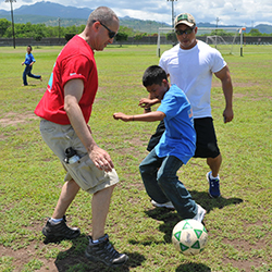 Father kicking a ball with his son.