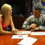 A women and a serviceman reviewing documents at a conference table