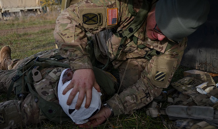 U.S. Army Sgt. Eric Puglio, right, of Foxtrot Battery, 1st Battalion, 41st Field Artillery Regiment, 1st Armored Brigade bandages Army Sgt. Derrick Rouse's head after he received a simulated injury. (U.S. Army photo by Staff Sgt. Carol A. Lehman)