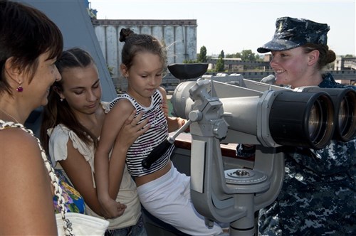 ODESSA, Ukraine - Ensign Julia Kranz, right, conducts a tour of the guided-missile destroyer USS Jason Dunham (DDG 109) for children of the Zhemchuzhinka Orphanage. Jason Dunham is on a scheduled deployment in support of maritime security operations and theater security cooperation efforts in the U.S. 6th Fleet area of responsibility.