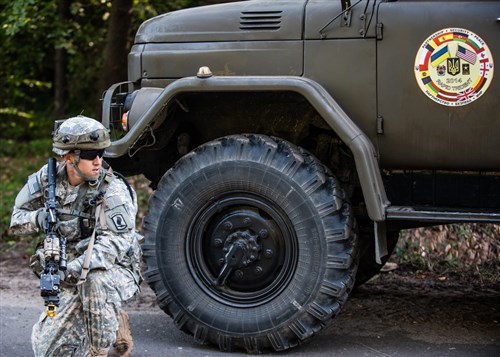 A Soldier from U.S. Army Europe’s Charlie Co., 173rd Airborne Brigade pulls security from the side of a Ukrainian military vehicle during a convoy exercise lane at Rapid Trident 2014. Rapid Trident is an annual U.S. Army Europe-conducted, Ukrainian-led multinational exercise designed to enhance interoperability with allied and partner nations while promoting regional stability and security.