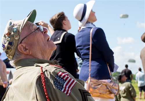 George Shenkle, World War II veteran and former U.S. Army Soldier with the Easy Company, 508th Parachute Infantry Regiment, 82nd Airborne Division, reacts as U.S. Army Soldiers parachute over the historic La Fiere drop zone near Sainte Mere Eglise, Normandy, France, June 7, 2015, to commemorate the 71st Anniversary of D-Day. More than 380 U.S. service members from Europe and affiliated D-Day historical units participated in the 71st Anniversary air drop as part of Joint Task Force D-Day 71. The task force, based in Sainte Mere Eglise, France, is supporting local events across Normandy, from June 2-8, 2015, to commemorate the selfless actions by all the Allies on D-Day that continue to resonate 71 years later. (U.S. Air Force Photo by Master Sgt. Brian Bahret)