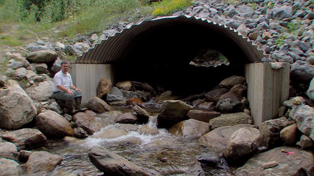 Rochester, Vt., July 29, 2012 -- U.S. Forest Service Civil Engineer Brian Austin sits outside a culvert on a tributary running through the Moosalamoo National Recreation Area in Arlington, Vermont. Tropical Storm Irene-damaged culverts in Rochester, Vermont will be similarly reconstructed, using rocks and sand to simulate a natural fish passage. 