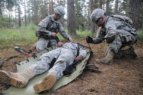 GRAFENWOEHR, Germany-- 1st Lt. Alan Vaugn (left), a first-time participant in the EFMB and laboratory officer assigned to the Landstuhl Regional Medical Center, straps a simulated casualty to a skid; in preparation for transport as part of Combat Testing Lane 3 during the 2011 U.S. Army Europe Expert Field Medical Badge Standardization and Testing held Aug. 1-13, 2011. (U.S. Army photo by Staff Sgt. Thomas Wheeler) 