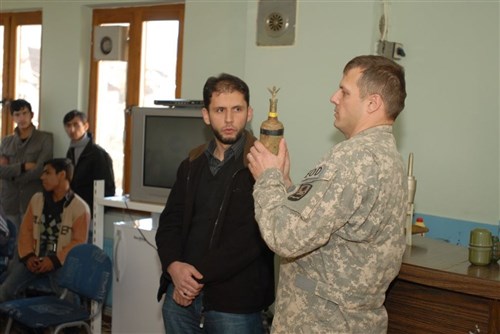 Sgt. 1st Class Kevin Vanklompenberg, operations sergeant, 745th EOD, Task Force Falcon, Multinational Battle Group East, shows a group of multiethnic children how some unexploded ordnance may be hidden inside other containers during a UXO class, Jan. 18 at a youth center in Kamenice/Kamenica. The class was designed to keep the children in the area aware of the risk UXO poses to them and how to react if they find any UXO. (U.S. Army photo by Pfc. Brian J. Holloran, 130th Public Affairs Detachment, Connecticut National Guard)