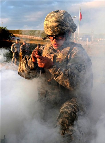 Spc. Autumn Ladines, a crew chief with the Arizona Army National Guard deployed to Kosovo with the Multinational Battle Group-East's Southern Command Post, assembles an M4 rifle, while a thick cloud of smoke limits her visibility during the stress shoot portion of the Multinational Battle Group-East's Best Warrior Competition held on Camp Bondsteel, Kosovo, July 10. (U.S. Army photo by: Staff Sgt. Thomas Duval, Multinational Battle Group-East public affairs)