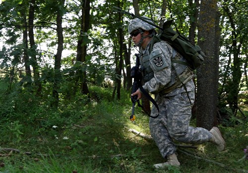 Spc. Autumn Ladines, a crew chief with the Arizona National Guard deployed to Kosovo with the Multinational Battle Group-East's Southern Command Post, navigates through a tree line during the Multinational Battle Group-East's Best Warrior Competition held on Camp Bondsteel, Kosovo, July 9. (U.S. Army photo by: Staff Sgt. Thomas Duval, Multinational Battle Group-East public affairs)